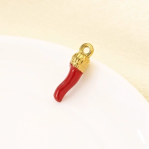 Macro shot of a red chili pepper pendant with gold metal clasp on white plate