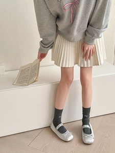 Gray calf-high socks with bow detail paired with white pleated skirt and silver flats