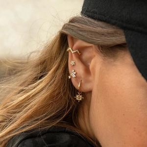 Close-up of golden butterfly ear cuff and star pendant earrings set on a model