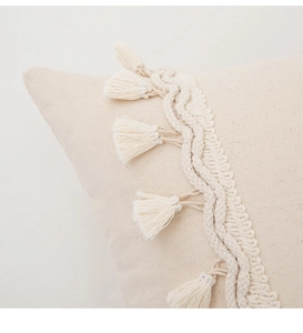 Detailed macro view of beige cotton-linen pillow cover with handcrafted tassel fringe edges