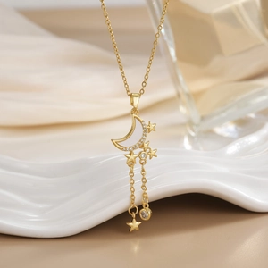 Detail of gold-plated celestial necklace with zircon-encrusted moon and star tassels