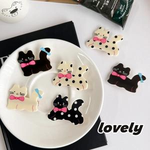 Cute cartoon cat hair clips with polka dots and pink bows in a stylish ceramic dish