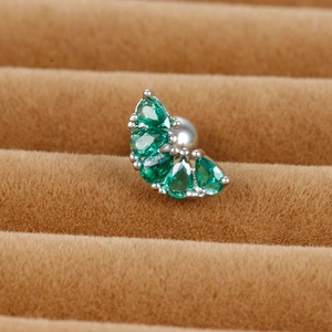 Macro view of green pear-cut zircon cartilage stud earring on brown velvet display