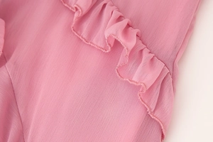 Détail macro du tissu rose à volants sur robe longue col en V montrant la couture