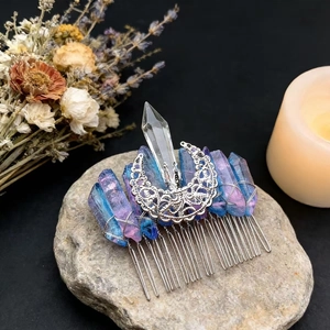 Detail view of handmade moon crystal hair comb on a natural stone with candlelight