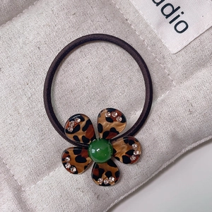 Detail of leopard print flower hair tie with green bead and sparkling rhinestones