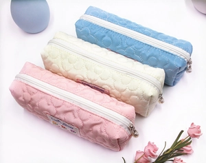 Close-up of quilted floral pencil cases with pearl charms in macaron pastel colors