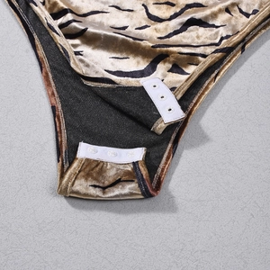 Detail of tiger print velvet bodysuit featuring bottom snap button closure design