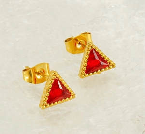 Macro shot of 18K gold triangular earrings featuring red zircon and beaded texture