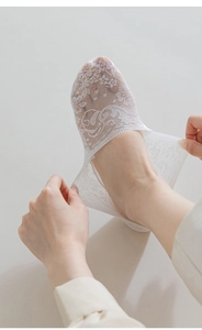 Close-up of white lace liner socks showing breathable floral texture and elastic stretch