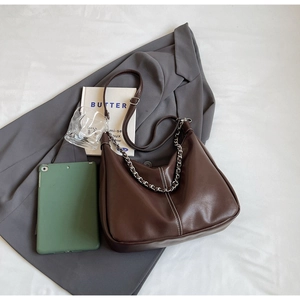 Flat lay of dark brown PU leather hobo bag with silver chain on a grey blazer