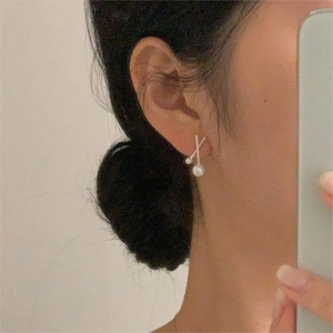 Elegant 925 silver cross-shaped earrings featuring two white pearls worn by a model