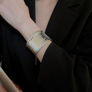 Close-up of minimalist silver wide open cuff bracelet with layered metallic stripes on wrist