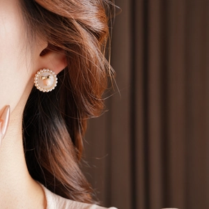 Detail of vintage flower pearl earrings with golden bow worn by a model in soft light