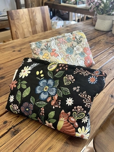 Close-up of black and beige embroidered canvas makeup bags with floral and cat patterns