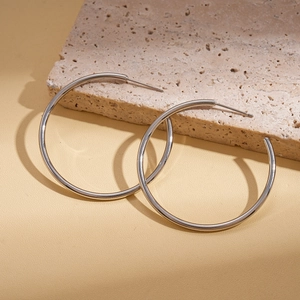 Detailed view of silver glossy geometric hoop earrings on a textured stone display