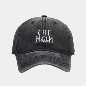 Detailed view of white CAT MOM embroidery on washed black cotton baseball cap fabric