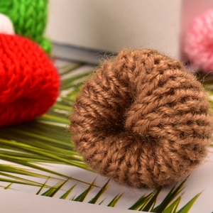 Close-up of brown knitted mini hat detail with thick wool texture and handmade finish