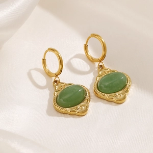 Vintage gold oval earrings with green gemstone pendants on elegant white silk fabric