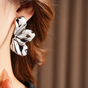 Close-up of a silver-tone abstract leaf earring worn by a model in a professional shot