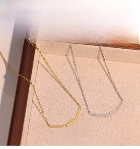 Detail view of gold and silver smile necklaces with zircon pavé on a textured tray