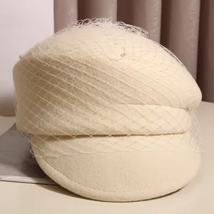 Close-up of beige wool beret featuring elegant mesh veil and delicate pearl accents