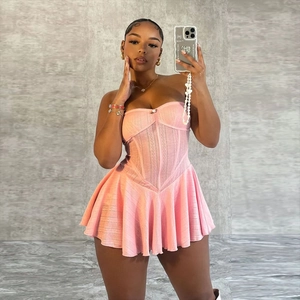 Pink strapless knitted corset dress with pleated skirt worn by a model in a studio