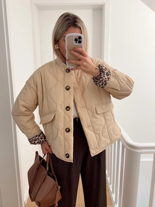 Detail of beige quilted jacket featuring leopard print cuffs and dark buttons decoration
