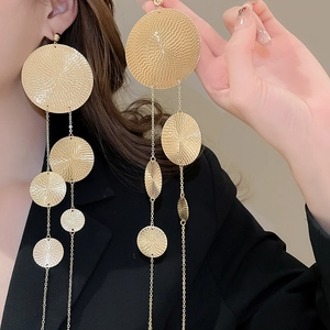 Detail of extra long gold tassel earrings with textured metal discs on model