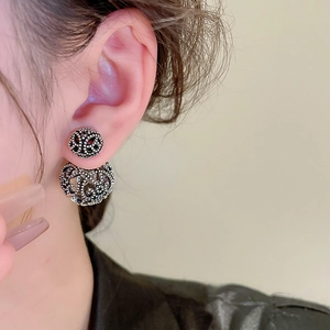 Detail of silver hollowed double ball earrings with intricate filigree on a model