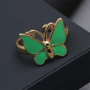 Close-up of golden butterfly ring with green enamel inlay on dark leather texture