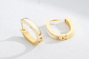 Detail of gold and white shell-textured stainless steel hoop earrings for women