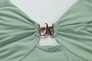 Detail of mint green dress with golden starfish metal buckle and ruched fabric texture