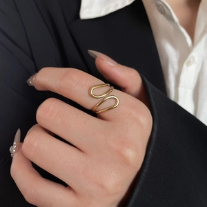 Close-up of a minimalist adjustable gold ring with a curved design worn on a finger