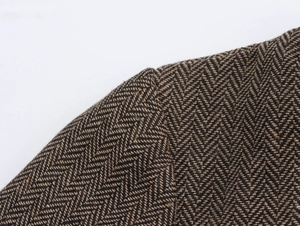 Gros plan détaillé sur la texture du tissu en tweed à chevrons marron de l'épaule