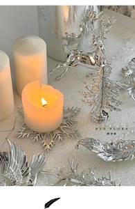 Silver Christmas deer and snowflake decorations with white candles and festive scenery