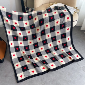 Detail of checkered scarf with red hearts on a sofa featuring soft fabric texture