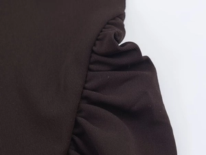 Macro view of chocolate brown ruched fabric detailing on a halter neck vacation dress