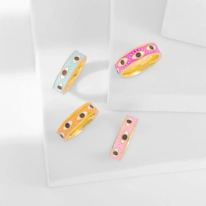 Detail showing colorful enamel evil eye rings in pink, orange, blue and pink on white blocks