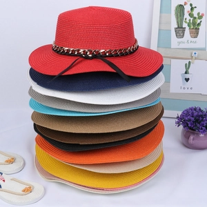 Detail of wide brim straw hats in multiple colors featuring metal chains and bow ties