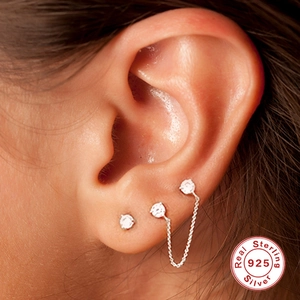 Sterling silver earring set with zircon studs and delicate chain shown on a model's ear