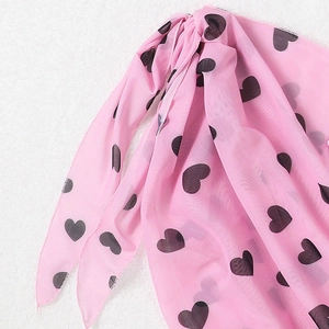 Vue détaillée du sarong en résille rose avec motifs de cœurs noirs et fermeture nouée