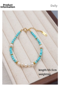 Macro detail of turquoise beads, pearls and K18 gold tag on beaded bracelet