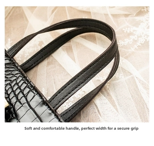 Close-up of black crocodile texture leather handbag with reinforced handle stitching