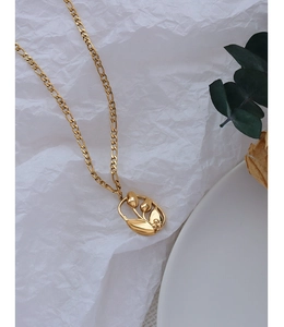 Gros plan d'un pendentif fleur de tulipe en or 18 carats sur une chaîne figaro élégante