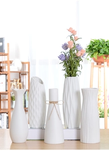 Close-up of white ceramic vases with geometric textures and pink artificial flowers