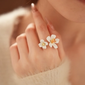 Detailed view of dual white floral ring with sparkling yellow zircons on finger