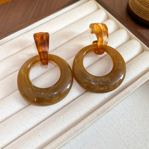 Macro view of vintage amber resin circular drop earrings on beige fabric tray