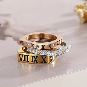 Dettaglio macro del set di tre anelli con numeri romani in oro, argento e oro rosa e strass