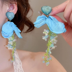 Detail of long tassel earrings with blue butterfly ribbon and handmade floral beads